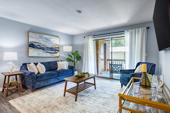 a living room with blue furniture and a sliding glass door to a balcony