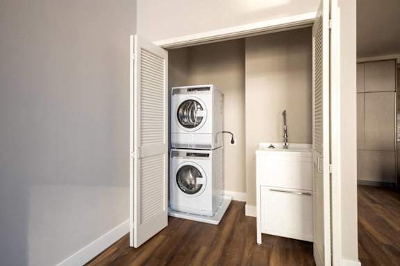 A white washing machine and dryer are stacked on top of each other in a small laundry room.