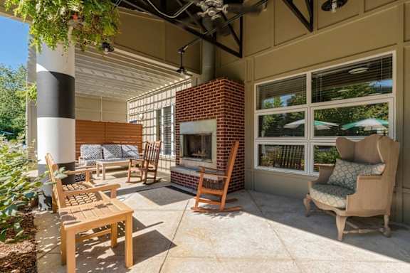 a covered patio with a fireplace and chairs at Village Club of Royal Oak, Royal Oak