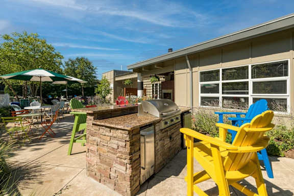 a patio with a barbecue grill and chairs at Village Club of Royal Oak, Royal Oak
