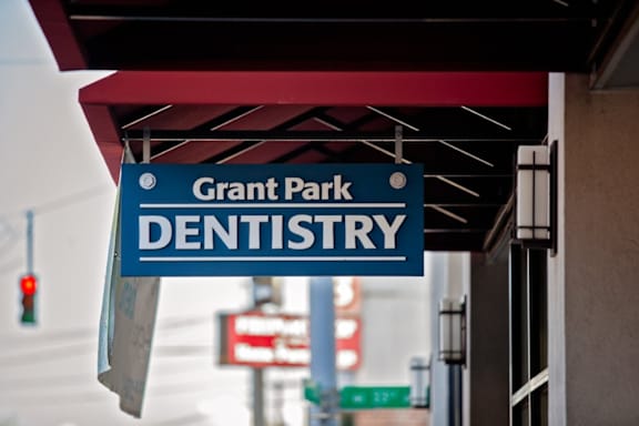 A sign for Grant Park Dentistry hangs from a building.