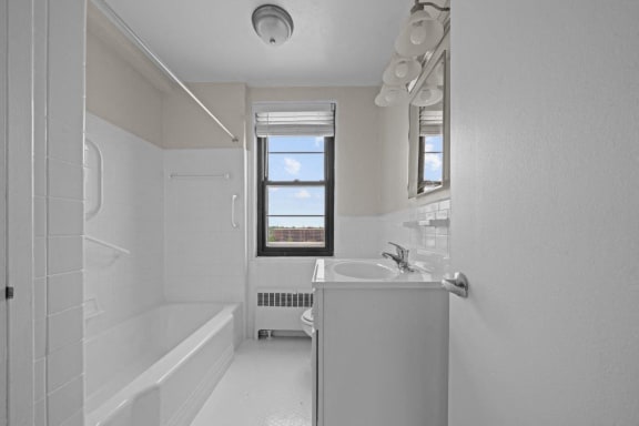 a white bathroom with a tub and a sink