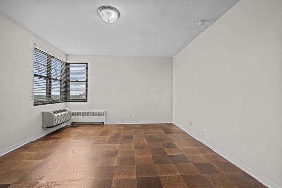 an empty living room with a large window and wooden floors