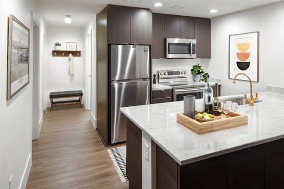 A modern kitchen with a refrigerator, microwave, and oven.