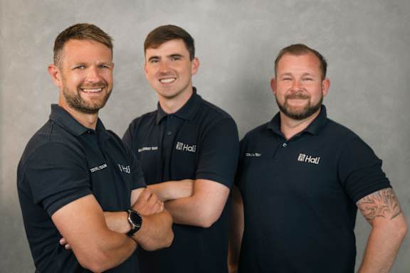 Three men wearing black shirts with the logo "it's Hall" on them.