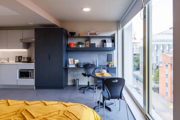 a bedroom with a bed and two chairs in front of a window