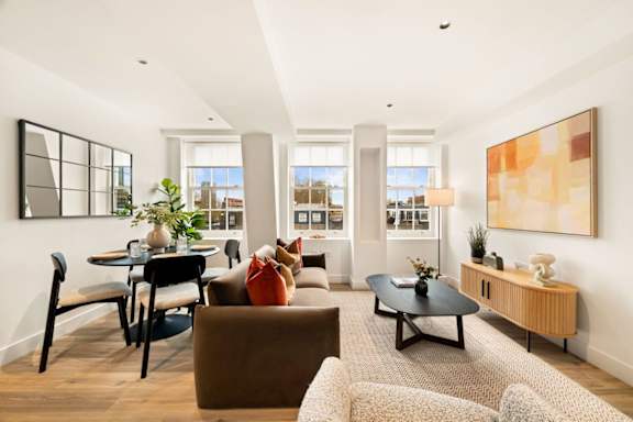 A living room with a brown couch, a black coffee table, and a large painting on the wall.