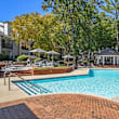 A wooden deck with lounge chairs and umbrellas in front of a building.