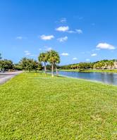 A grassy area with a pond and a building in the background.