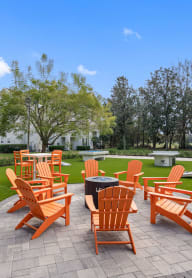 an outdoor patio with orange chairs and a fire pit