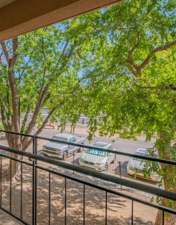 a balcony with a view of a tree and cars on the street