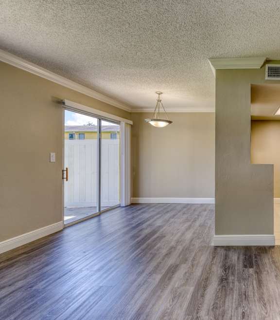 the spacious living room and dining room of an empty home with a hard wood floor