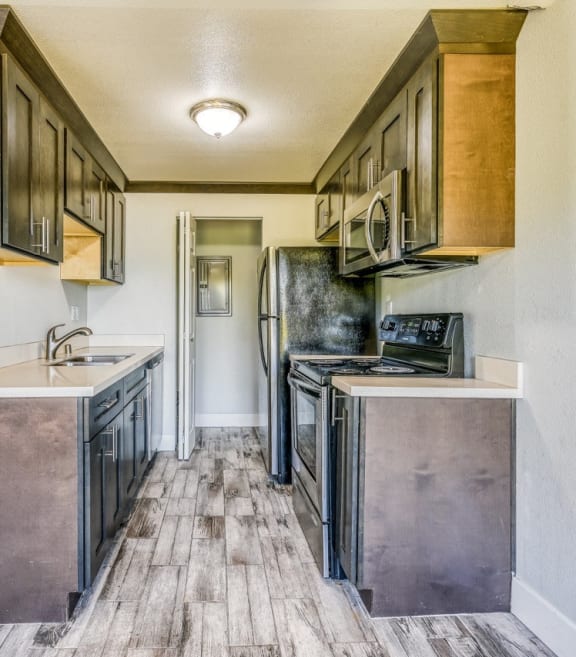 an empty kitchen with stainless steel appliances and wood flooring