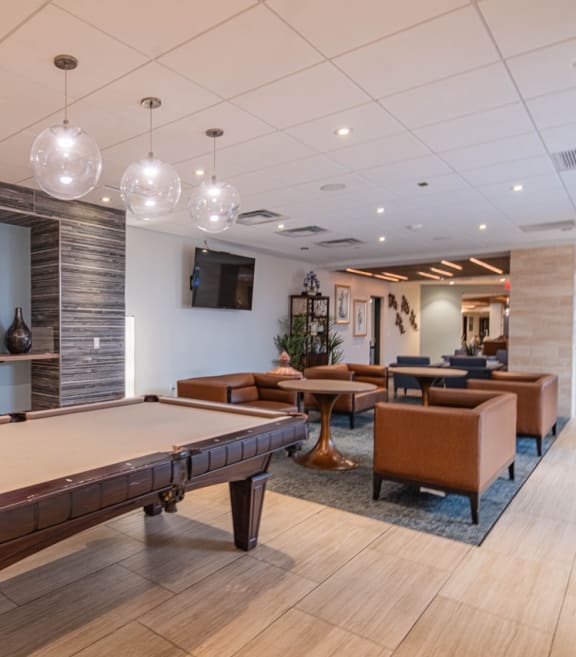 a billiards table in the lobby of a community room with tables and chairs