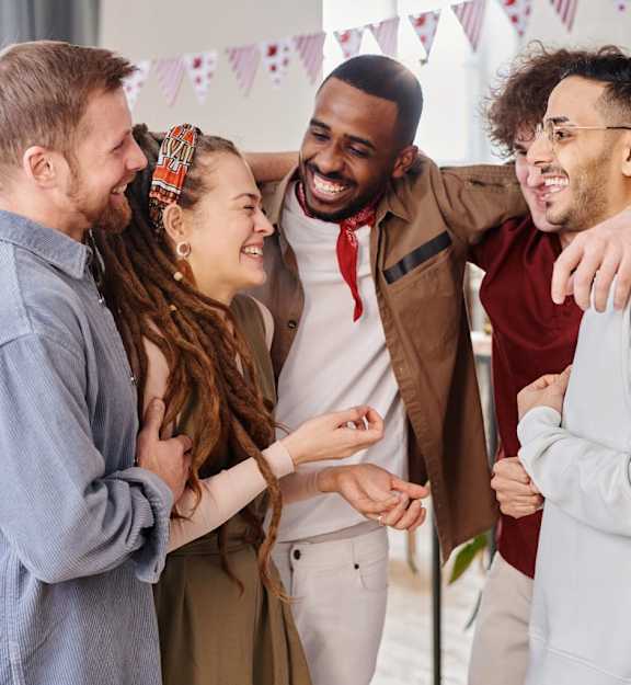 Four people hug each other in a room.