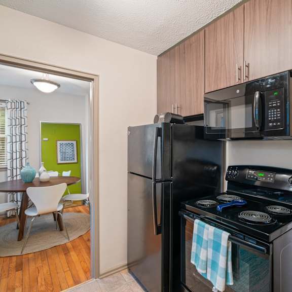 A black stove and microwave in a kitchen with wooden cabinets.