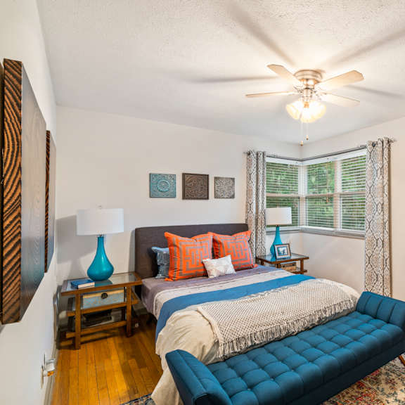 A bedroom with a bed, a couch, and a ceiling fan.