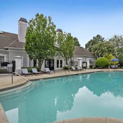 A large swimming pool surrounded by lounge chairs and trees.