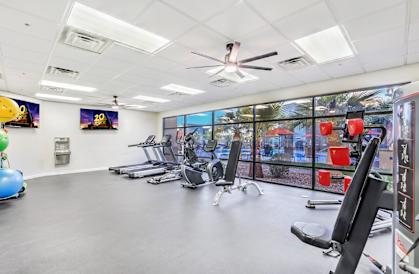 A gym with a variety of equipment including treadmills, exercise bikes, and a fan.