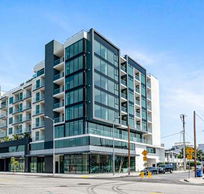 A modern multi-story building with glass windows and balconies.