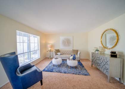 a living room with a blue chair and a couch at Villas del Tesoro Apartments, Dallas, TX, 75228