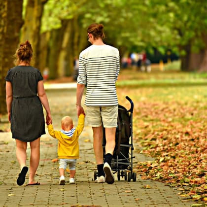 a family walking through a park with a baby in a stroller