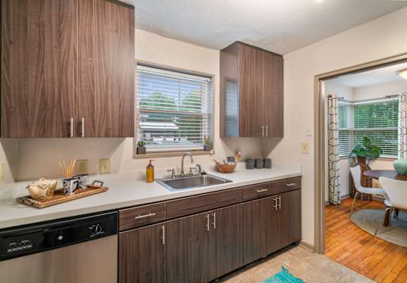 A kitchen with wooden cabinets and a black dishwasher.