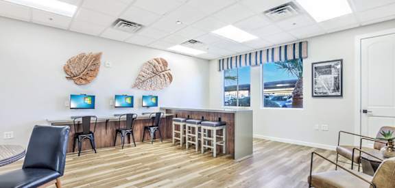 A room with a wooden floor and a wall with three framed pictures of leaves on it.