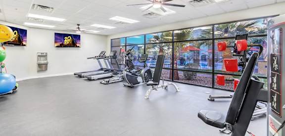 A gym with a variety of equipment including treadmills, exercise bikes, and a fan.