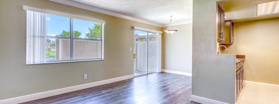 an empty living room with hard wood floors and a window