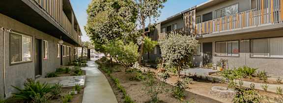 A concrete pathway leads through a landscaped courtyard between two rows of townhouses.