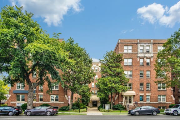 A row of red brick apartment buildings with trees in front.