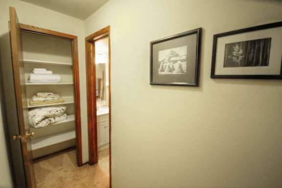 a bathroom with a closet and a mirror and a door to a room with towels