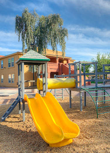 A basketball court with a bench on the side and two houses in the background.
