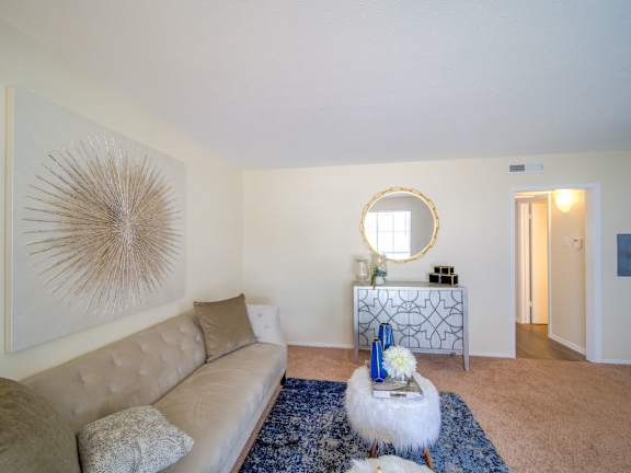a living room with a beige couch and a mirror