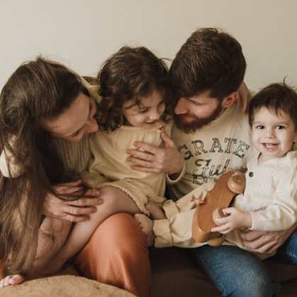a family of four sitting on a couch with a teddy bear