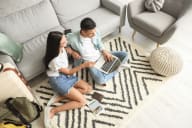 young couple sitting on the floor in the living room using laptop