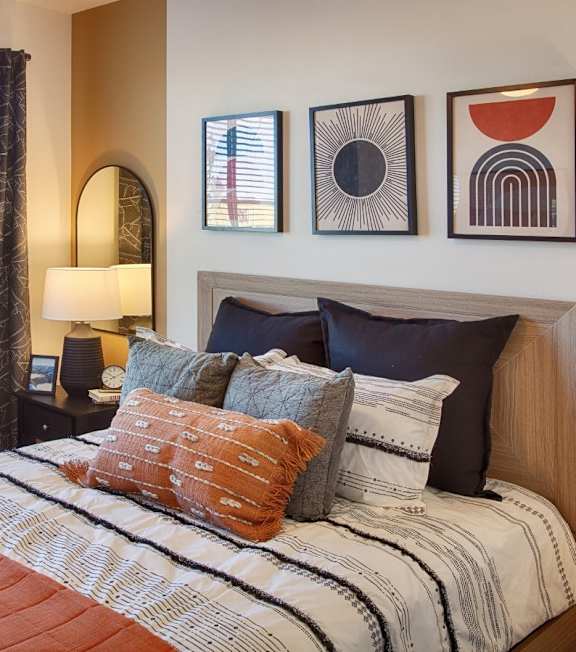 A bedroom with a bed, nightstand, and three wall art pieces.