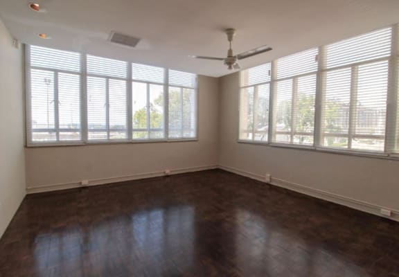an empty room with windows and a ceiling fan