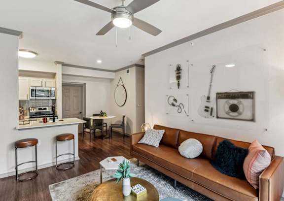 A living room with a brown couch and a ceiling fan.