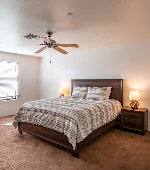 A bedroom with a bed, nightstand, and window.