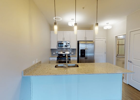 A kitchen with a blue island and stainless steel appliances.