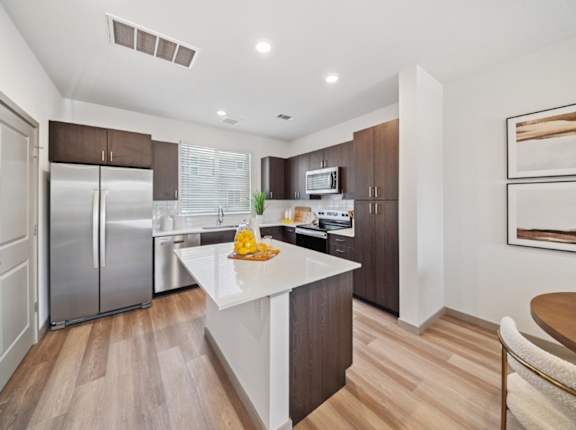A modern kitchen with a white island and stainless steel appliances.