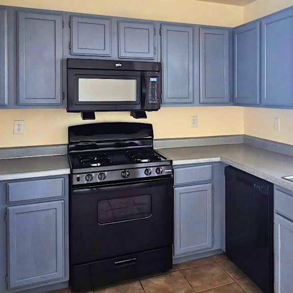 A kitchen with a black stove and cabinets.