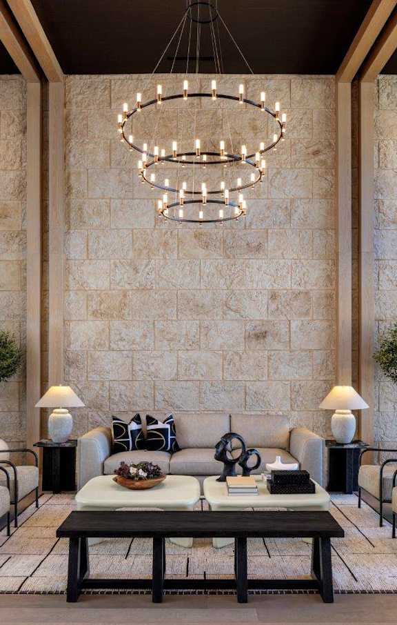 A modern living room with a stone wall and a chandelier.