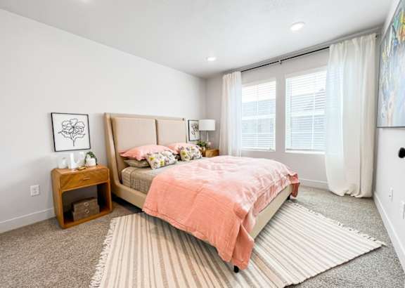 A bedroom with a bed, nightstand, and window.