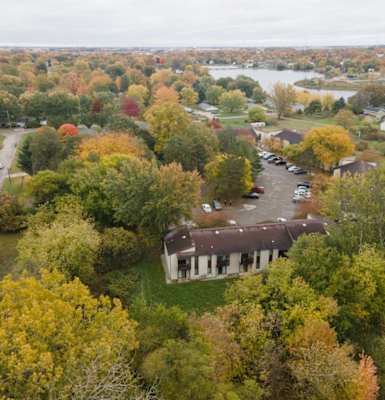 an aerial view of a house surrounded by trees and a river in the background