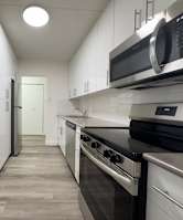 A modern kitchen with white cabinets and stainless steel appliances.