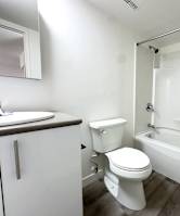 A white toilet sits next to a white bathtub in a small bathroom.