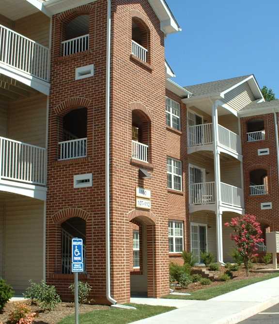 A red brick apartment building with a blue and white sign in front.